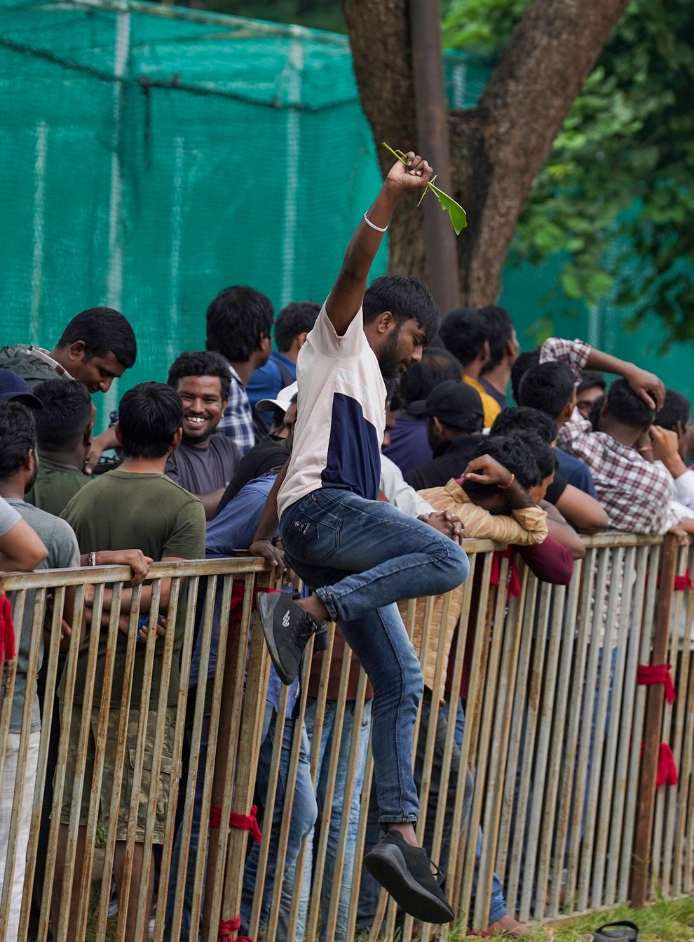 A man jumps a railing to take a break as people line up to buy tickets for the third Twenty20 cricket match between India and Australia at Gymkhana grounds in Hyderabad, India (Mahesh Kumar/AP)