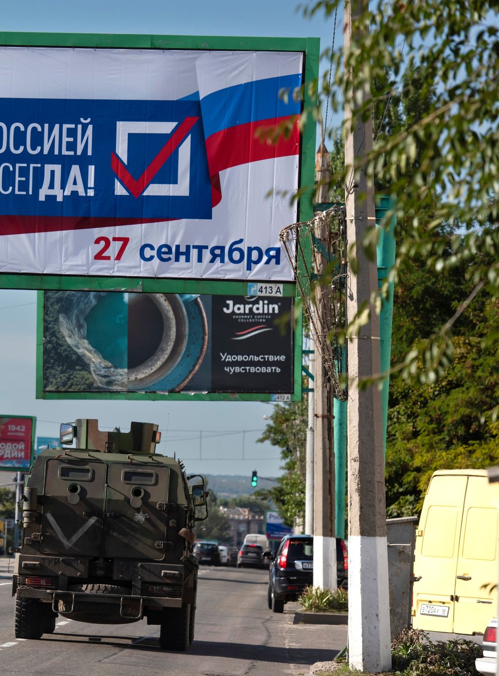 A military vehicle drives along a street with a billboard that reads: ‘With Russia forever, September 27’, prior to a referendum in Luhansk (AP)
