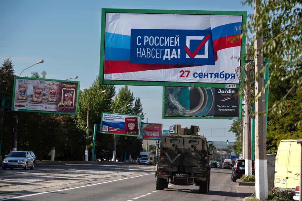 A military vehicle drives along a street with a billboard that reads: ‘With Russia forever, September 27’, prior to a referendum in Luhansk (AP)