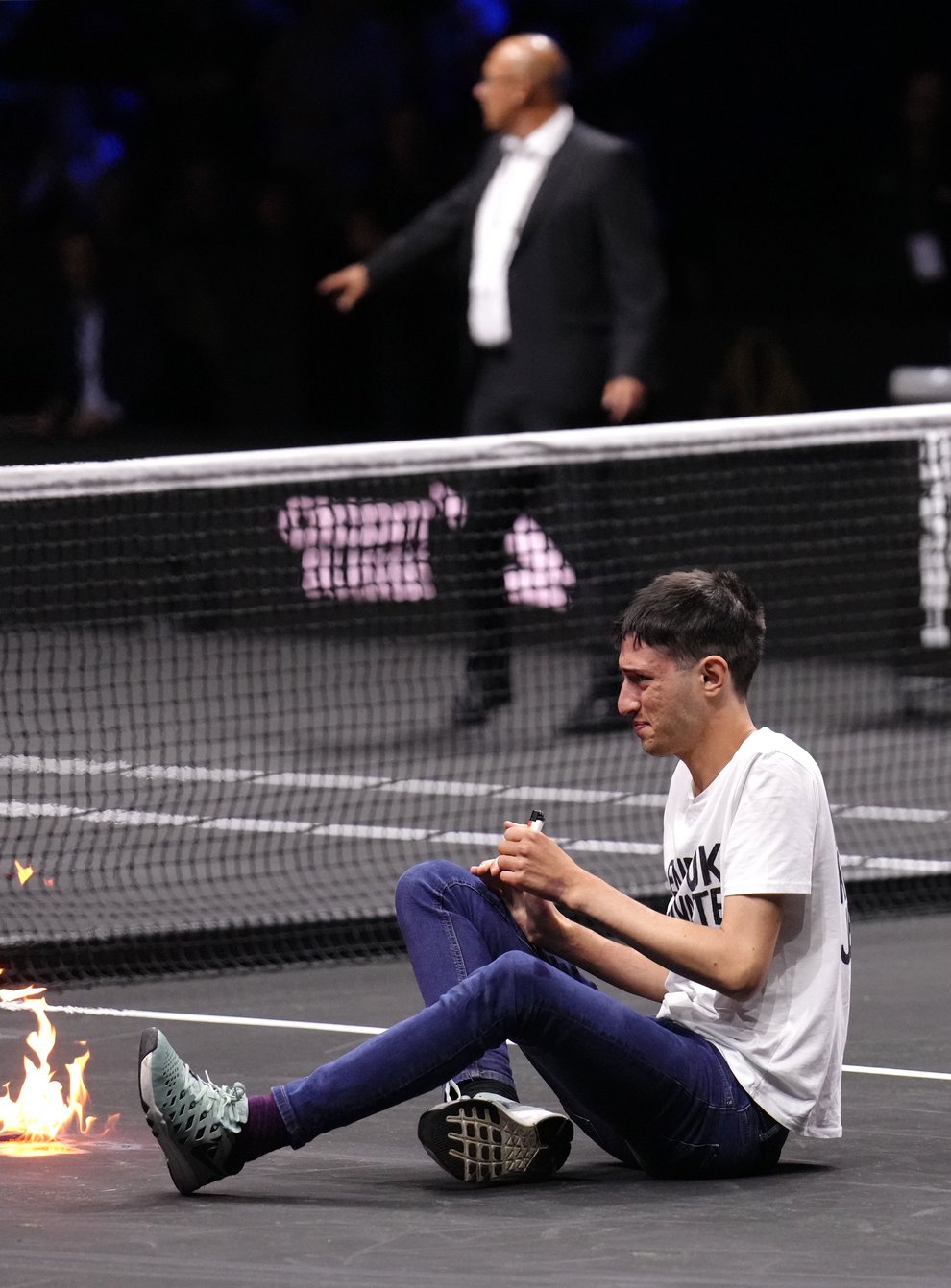A protester lights a fire on the court at the Laver Cup (John Walton/PA)