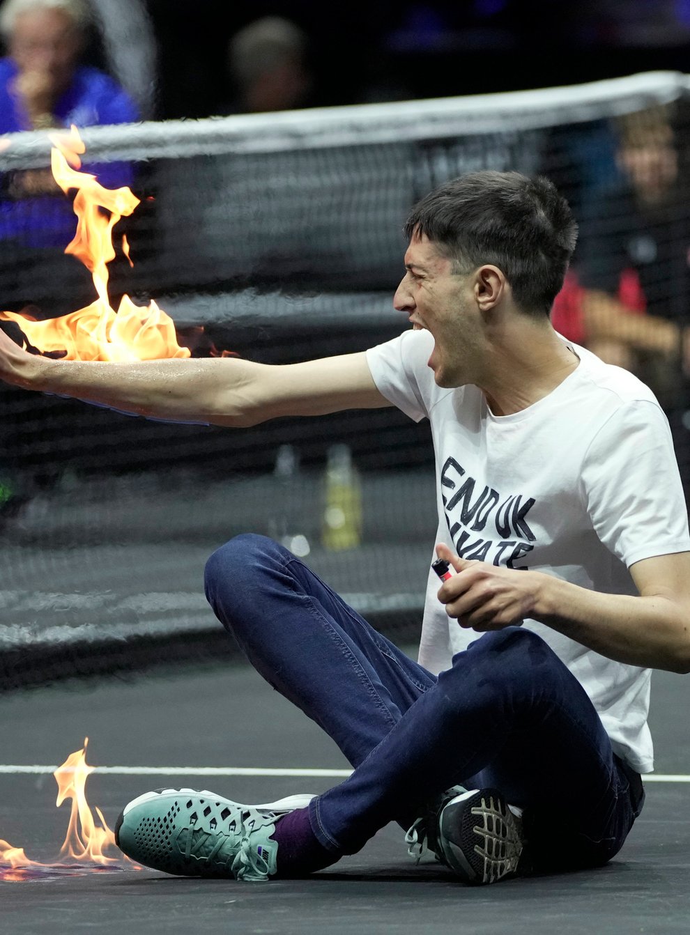 A protester lights his arm on fire on the court on day one of the Laver Cup (Kin Cheung/AP)