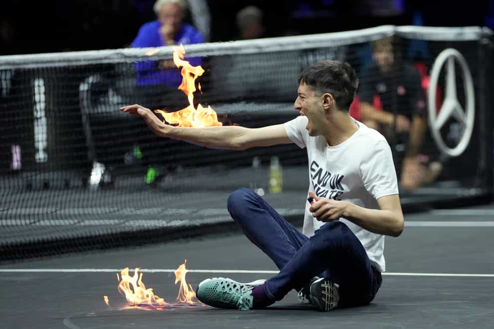 A protester lights his arm on fire on the court on day one of the Laver Cup (Kin Cheung/AP)