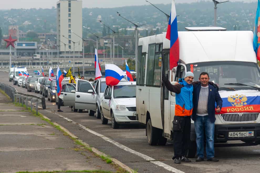 Two men pose for a photo in front of a motorcade organised to support voting in a Russian-backed referendum in Luhansk (AP Photo)