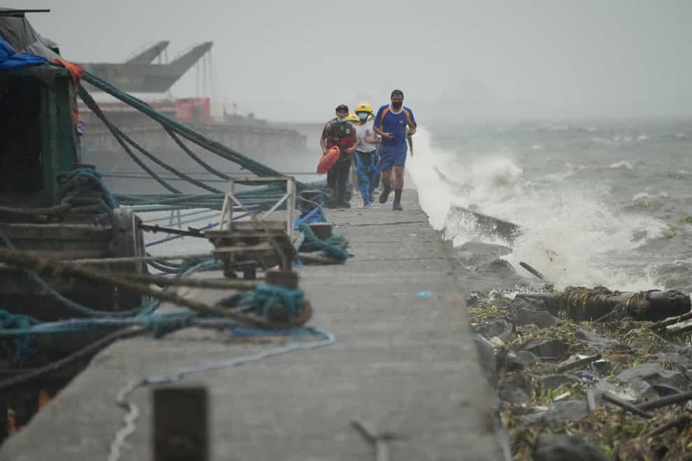 Rescuers run as they check residents living in the district of Tondo (Aaron Favila/AP)