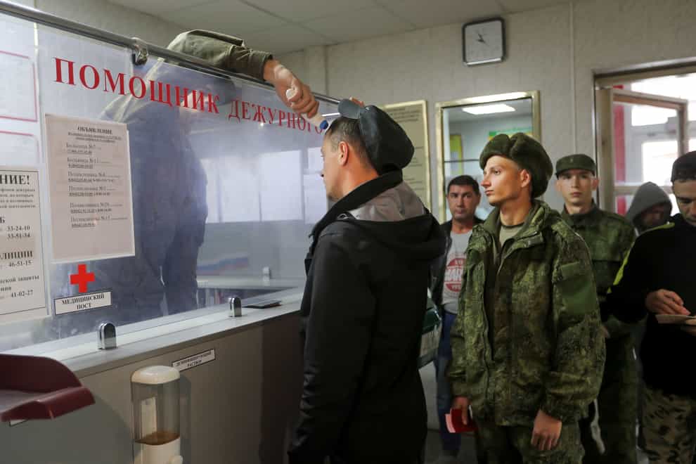 A Russian officer checks the temperature of recruits as they line up to be registered at a military recruitment centre in Volgograd, Russia (AP Photo)