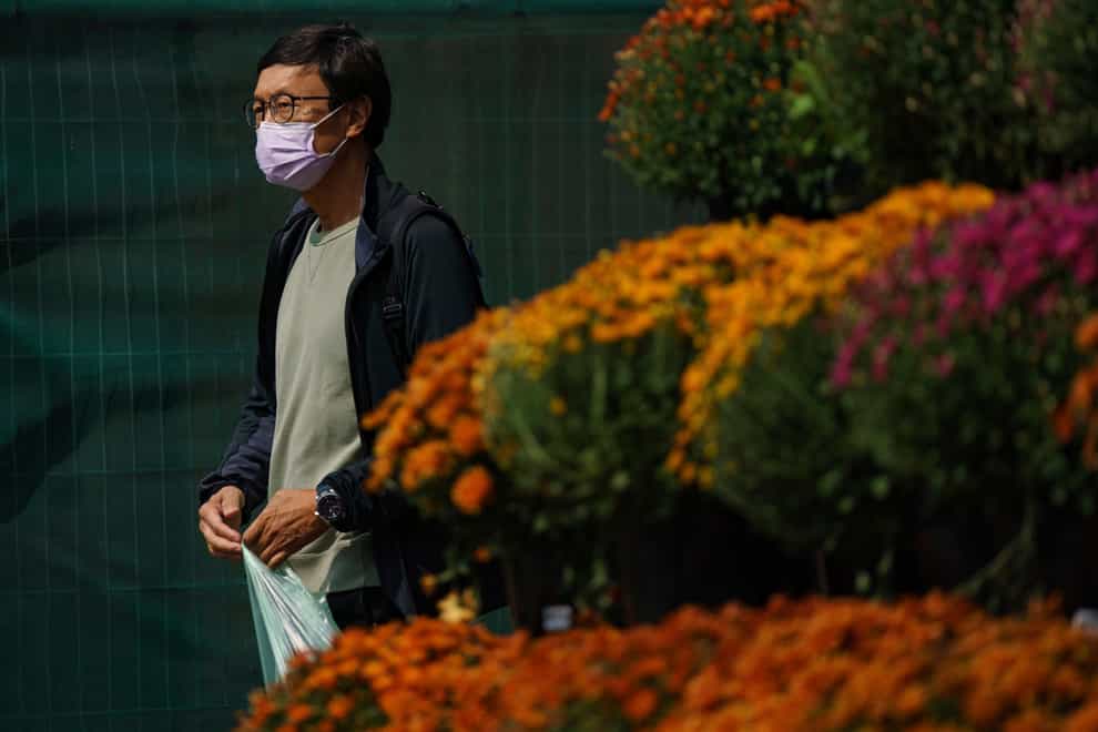 A person wears a mask while walking past a flower display in front of a supermarket in Front Street East, Toronto (Alex Lupul /The Canadian Press/AP)