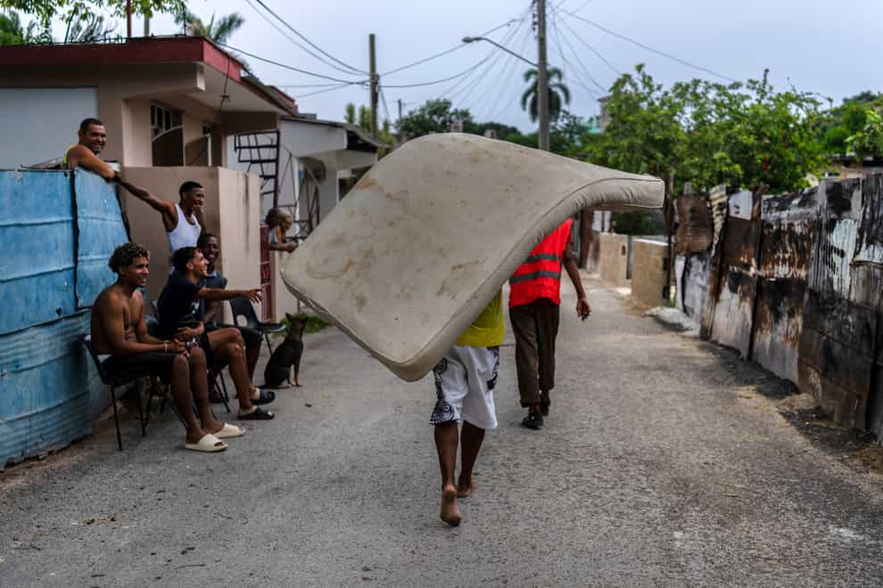 Residents of the El Fanguito neighborhood carry a mattress to a safe place in preparation for the arrival of Hurricane Ian, in Havana, Cuba, Monday, Sept. 26, 2022. Hurricane Ian is growing stronger as it approached the western tip of Cuba on a track to hit the west coast of Florida as a major hurricane as early as Wednesday. (AP Photo/Ramon Espinosa)