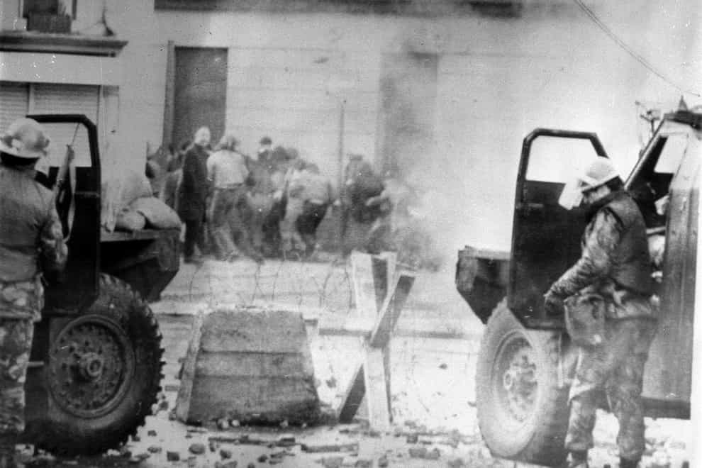 Soldiers take cover behind their sandbagged armoured cars while dispersing rioters with CS gas in Londonderry, where an illegal civil rights march culminated in a clash between troops and demonstrators, which resulted in 13 people being shot dead (PA)