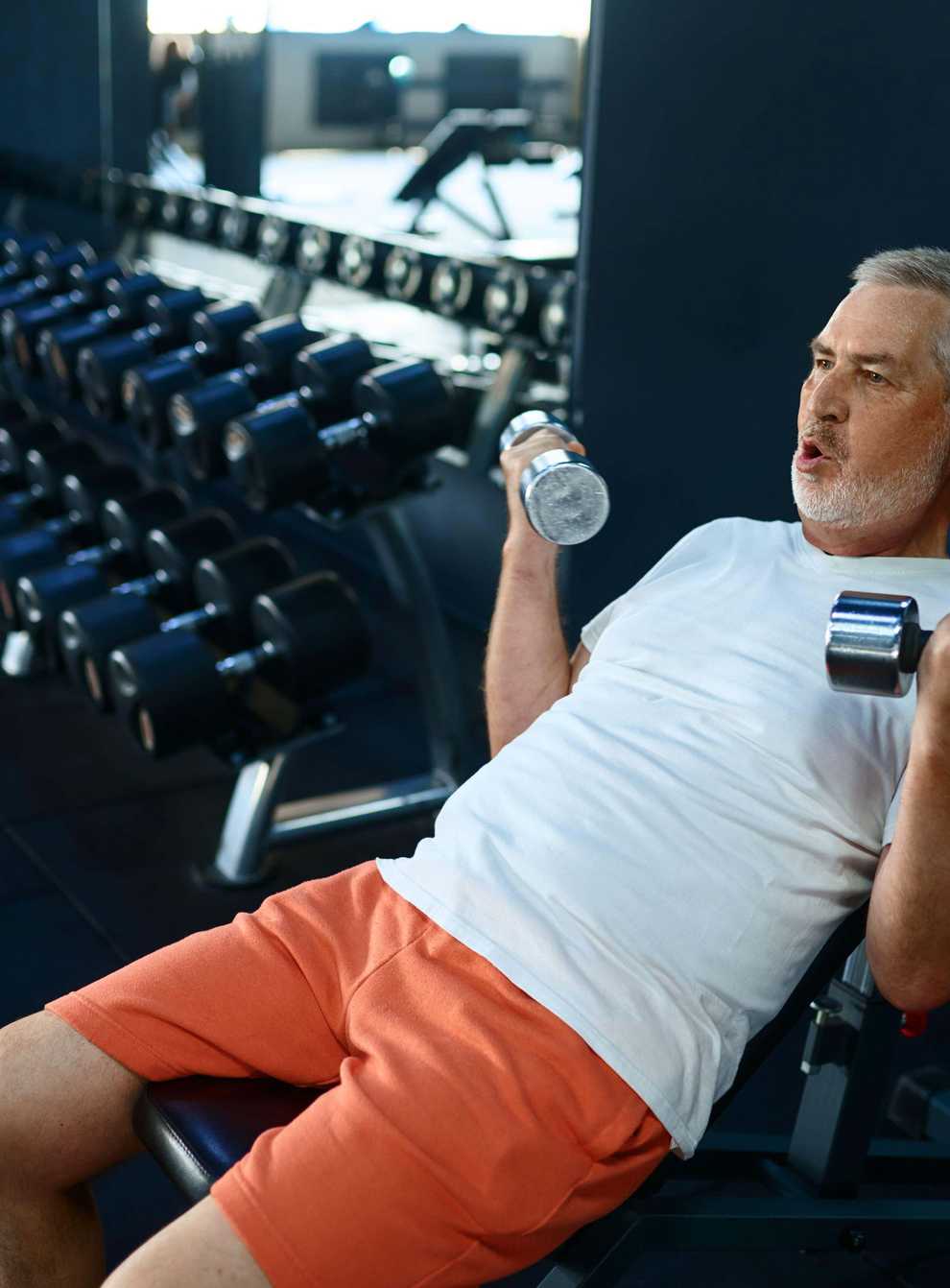 2H3MK2F Elderly man, workout with dumbbells on bench, gym