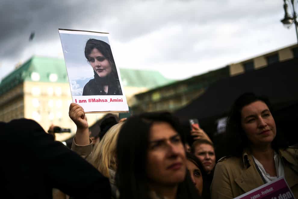A woman holds a photo of Iranian Mahsa Amini during a protest against her death, in Berlin, Germany, Wednesday, Sept. 28, 2022. Amini, a 22-year-old woman who died in Iran while in police custody, was arrested by Iran’s morality police for allegedly violating its strictly-enforced dress code. (AP Photo/Markus Schreiber)