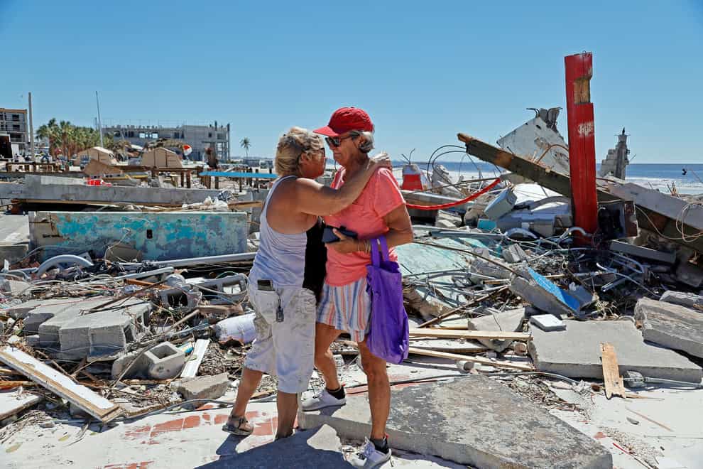 People embrace as they survey the wreckage of their businesses on the island of Fort Myers Beach, Florida (South Florida Sun-Sentinel via AP)