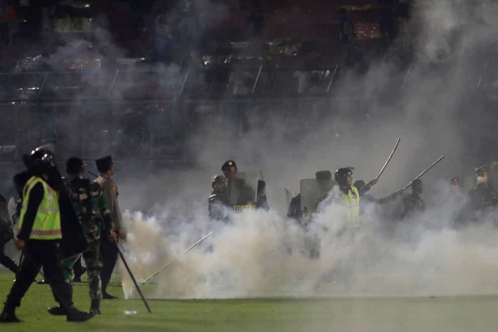 Police officers and soldiers stand in tear gas smoke at Kanjuruhan Stadium in Malang, East Java, Indonesia (Yudha Prabowo/AP)