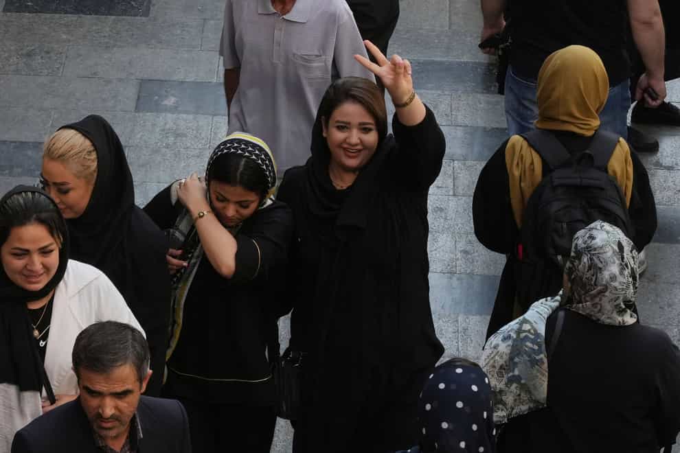 A woman flashes a victory sign as she walks in the old main bazaar in Tehran (Vahid Salemi/AP)