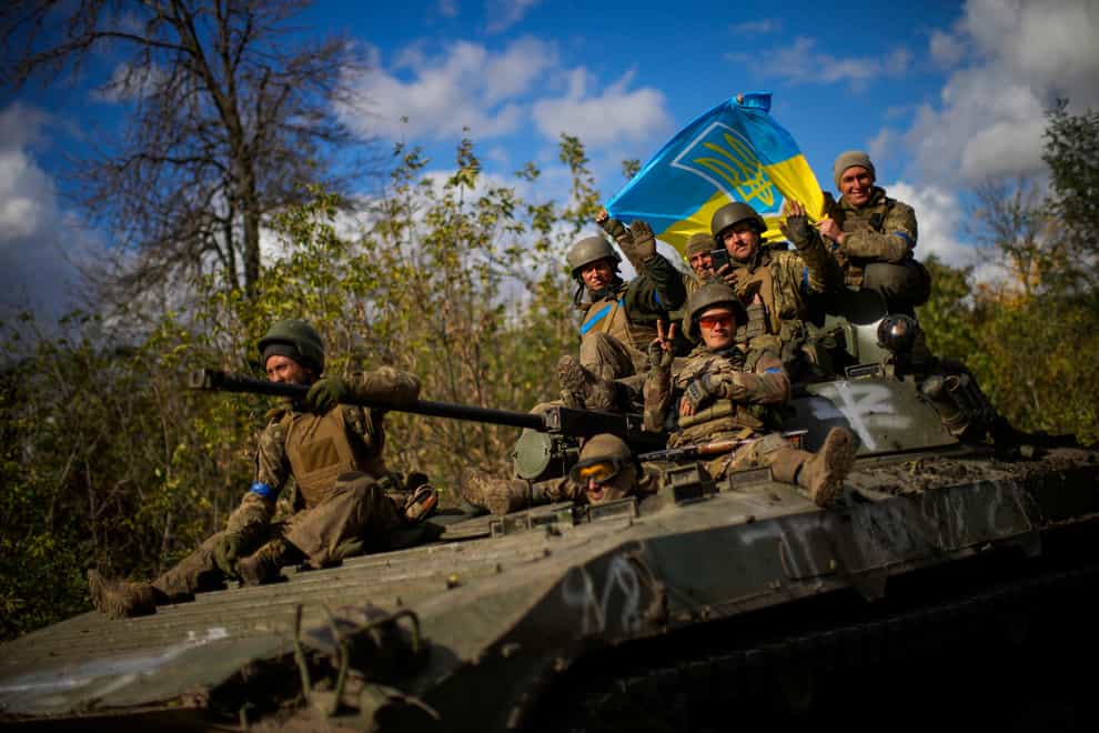 Ukrainian soldiers sit on an armoured vehicle as they drive between Izium and Lyman in Ukraine (Francisco Seco/AP)