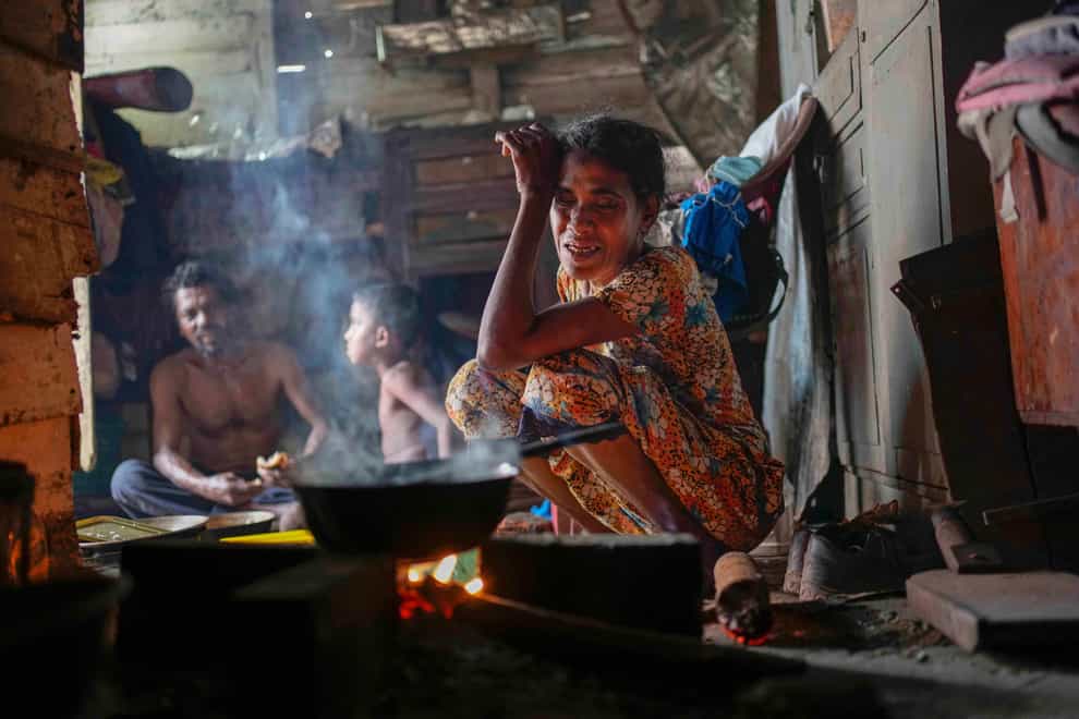 A woman sits by the fireplace at meal time in a shanty in Colombo (AP)