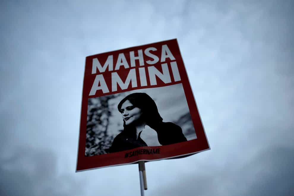 A woman holds a placard with a picture of Iranian Mahsa Amini (Markus Schreiber/AP)