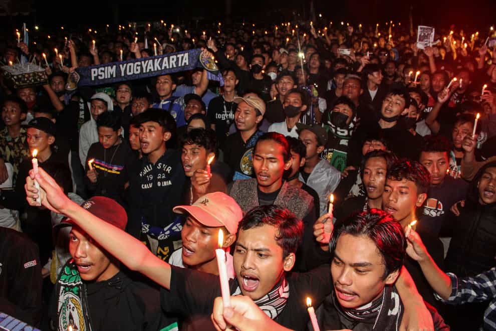 Soccer fans chant slogans during a candle light vigil for the victims of Saturday’s soccer stampede, in Sleman, Indonesia, Thursday, Oct. 6, 2022. Indonesian police said Thursday they are bringing criminal charges against three officers and three civilians for their roles in the deaths of more than 100 people when police fired tear gas in a soccer stadium after a match, setting off a panicked run for the exits in which many were crushed. (AP Photo/Slamet Riyadi)