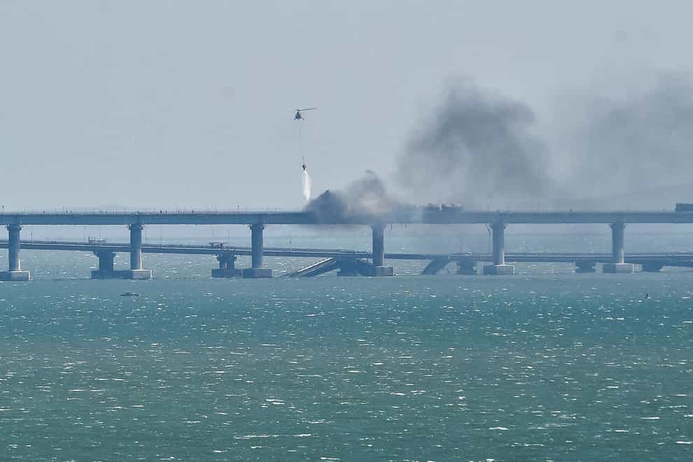 A helicopter drops water to stop fire on Crimean Bridge connecting Russian mainland and Crimean peninsula over the Kerch Strait, in Kerch, Crimea, Saturday, Oct. 8, 2022. Russian authorities say a truck bomb has caused a fire and the collapse of a section of a bridge linking Russia-annexed Crimea with Russia. The bridge is a key supply artery for Moscow’s faltering war effort in southern Ukraine. (AP Photo)
