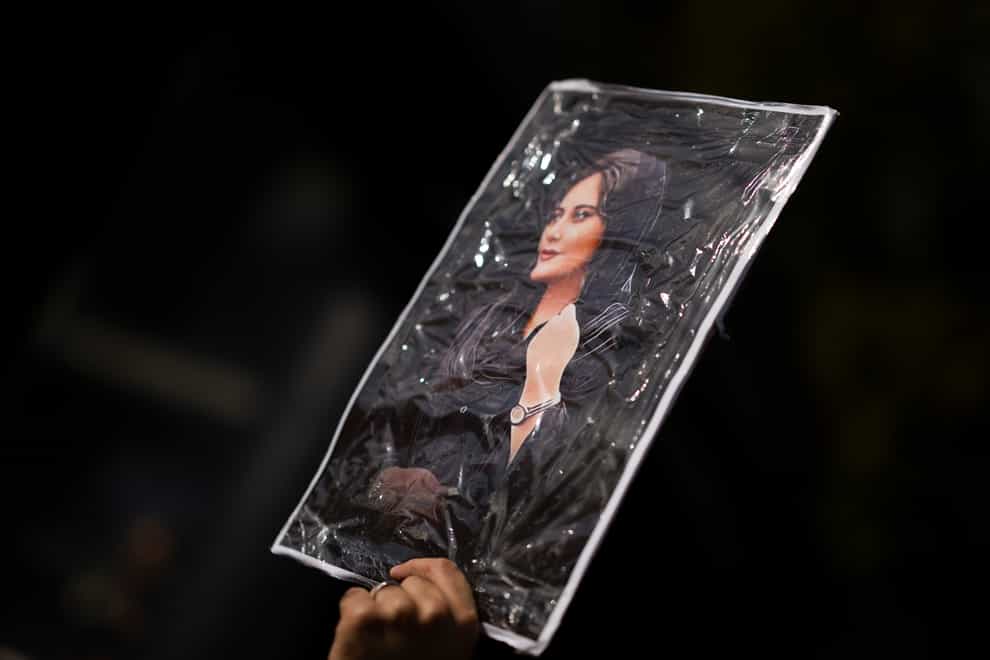A protester holds a portrait of Mahsa Amini as thousands showed their support for Iranian protesters standing up to their leadership over the death of Amini in police custody, during a demonstration in The Netherlands, Saturday, Oct. 8, 2022 (Peter Dejong/AP/PA)
