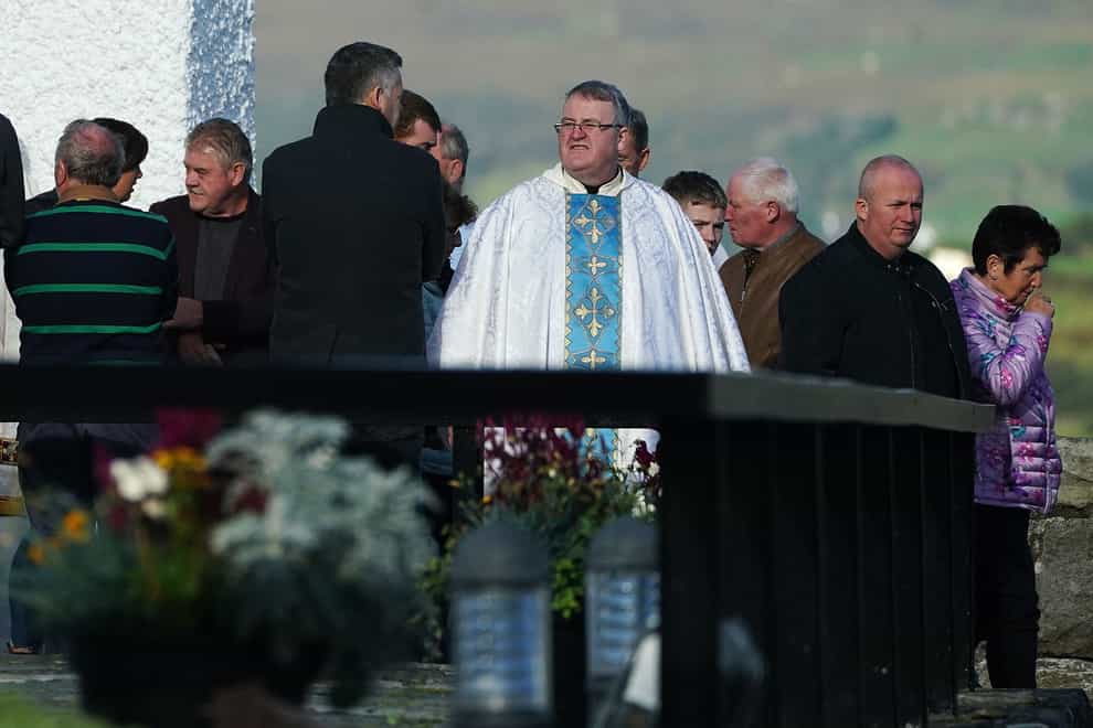 Father John Joe Duffy with members of the public as they leave St Michael’s Church Creeslough (Brian Lawless/PA)