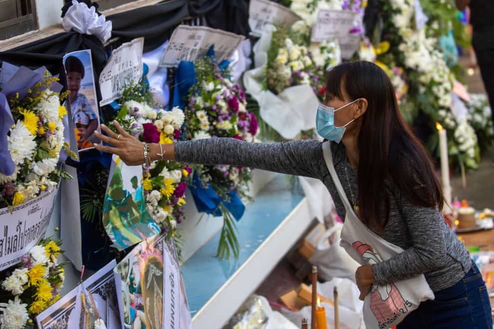 A woman touches a photo of one of the victims of the mass killing (Wason Wanichakorn/AP/PA)