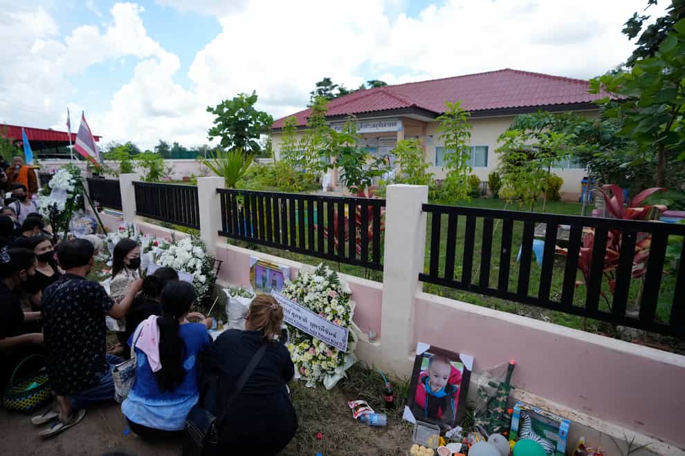 People pray for the victims of a mass killing attack outside the gate of the Young Children’s Development Centre in the rural town of Uthai Sawan, north-eastern Thailand (Sakchai Lalit/AP)