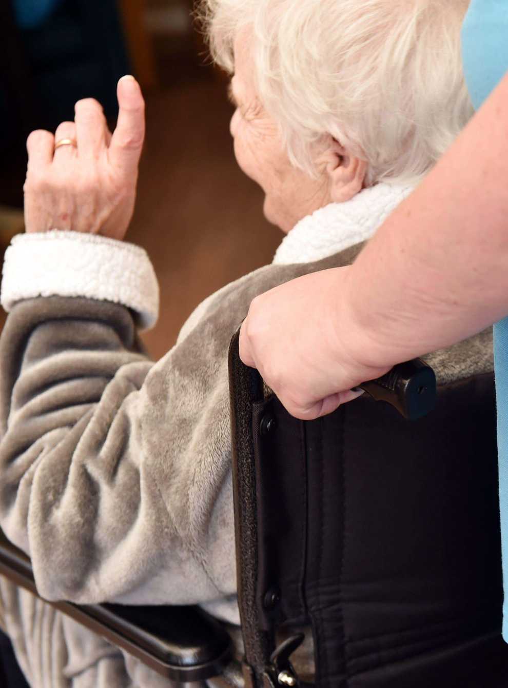 A care worker helps move an elderly person in a care home ( Paula Solloway/Alamy Stock Photo)