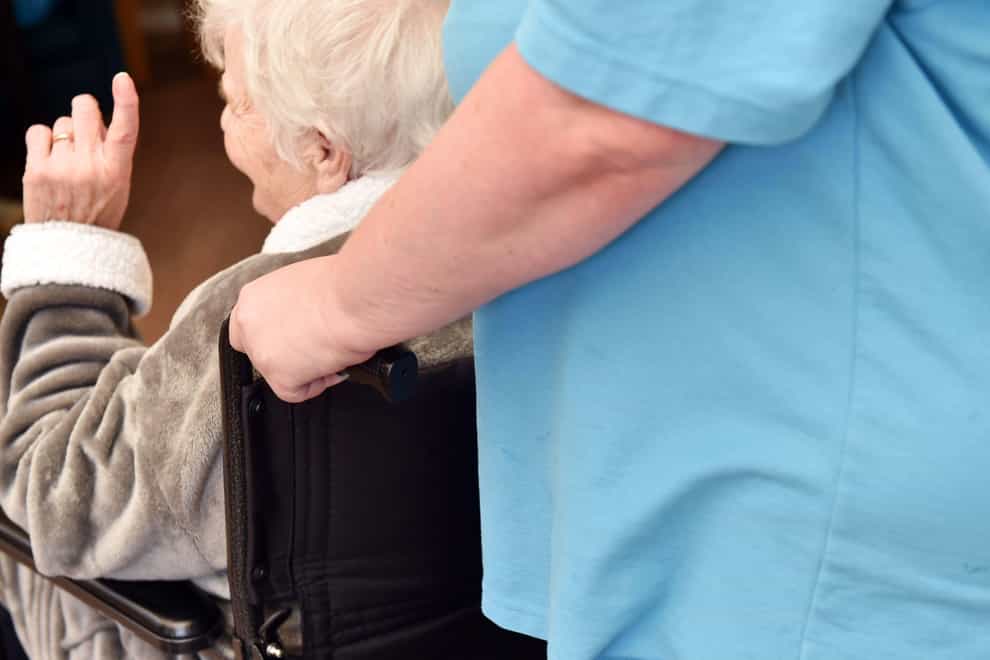 A care worker helps move an elderly person in a care home ( Paula Solloway/Alamy Stock Photo)