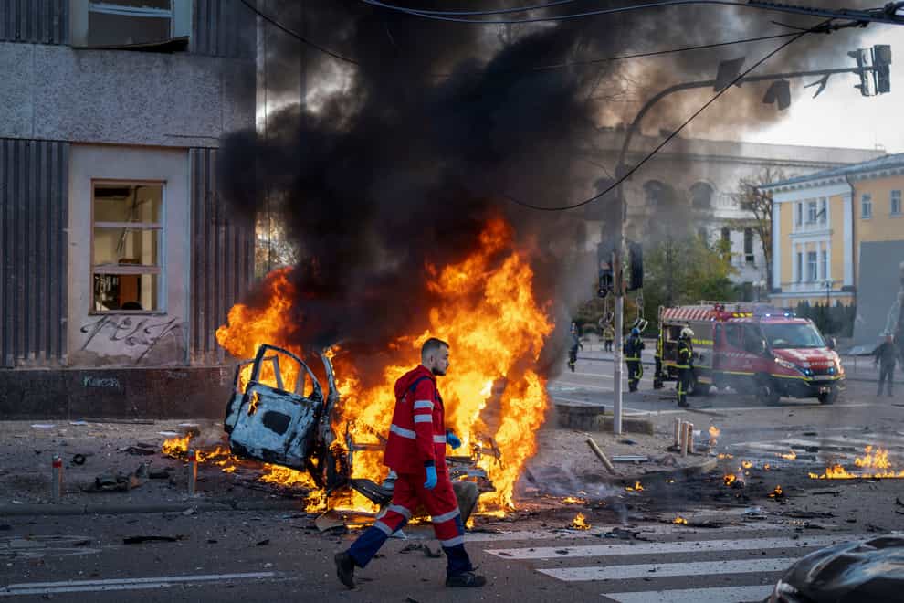 A medical worker runs past a burning car after a Russian attack in Kyiv, Ukraine (Roman Hrytsyna/AP)