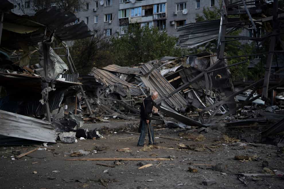 An elderly man walks past a car shop that was destroyed after a Russian attack in Zaporizhzhia, Ukraine (Leo Correa/AP)