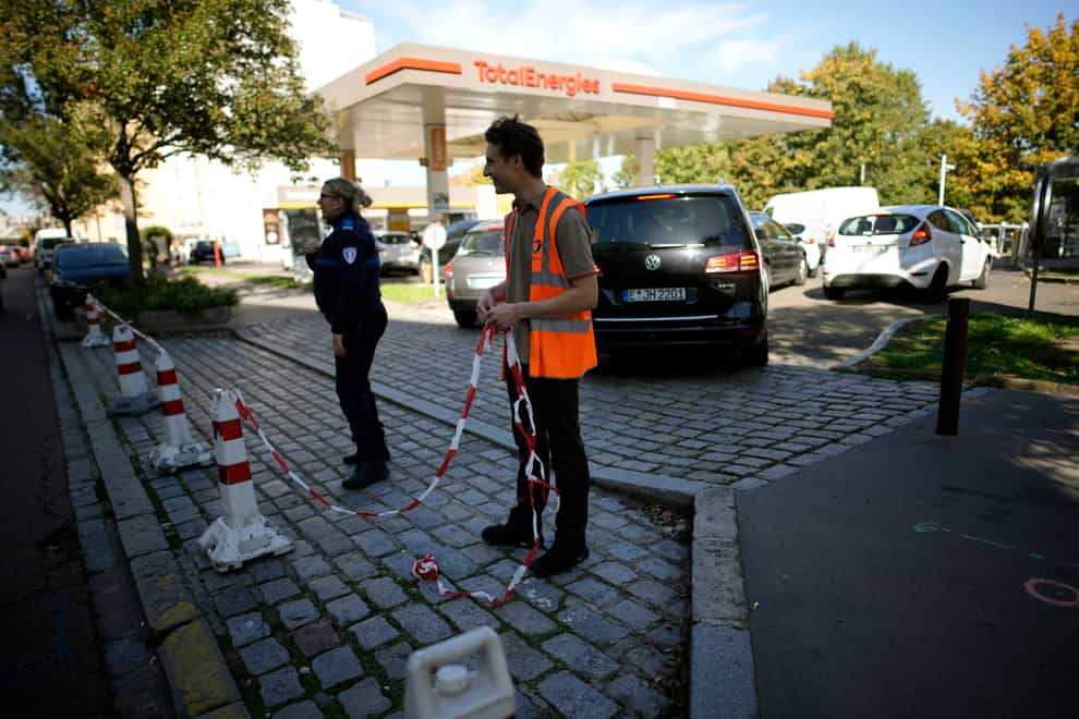 A petrol station worker and a police officer set up a ribbon as they close a petrol station (AP)