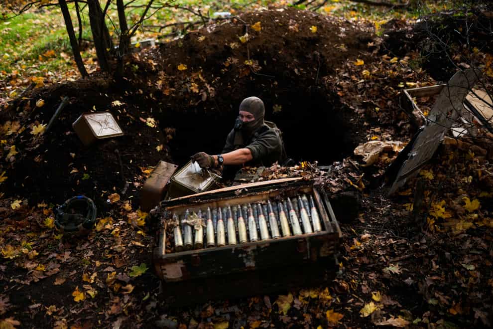 A Ukrainian territorial defence de-miner takes Russian ammunition left behind as his team clears mines near Grakove village, Ukraine (AP)