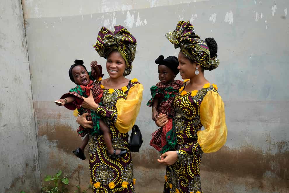 Twins Oladapo Taiwo, left, and Oladapo Kehinde, 21, pose for photographs holding relatives’ twins during the Annual twin festival in Igbo-Ora, south-west Nigeria (AP)