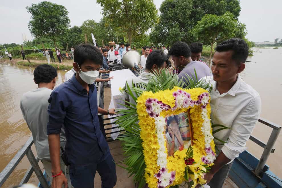 A portrait photo of a teen victim, Chanda July, is carried by her relative during her funeral procession in Koh Chamroeun village (AP)