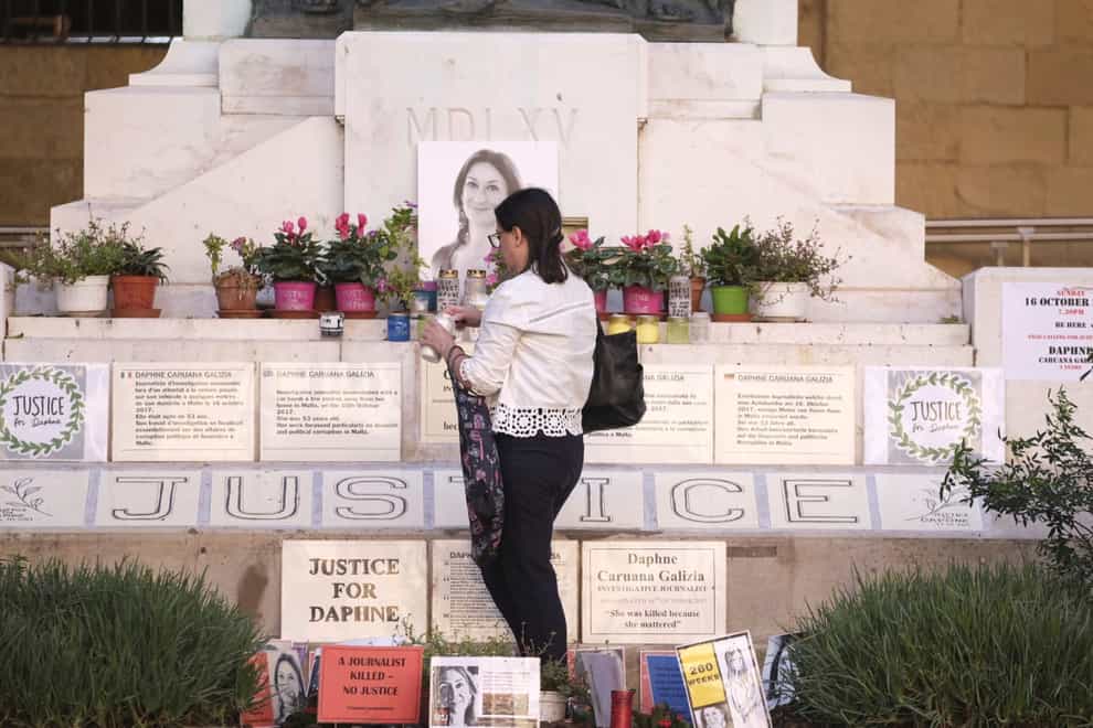 Mandy Mallia, sister of journalist Daphne Caruana Galizia, lights candles in front of a picture of her sister in Valletta (Jonathan Borg/AP)