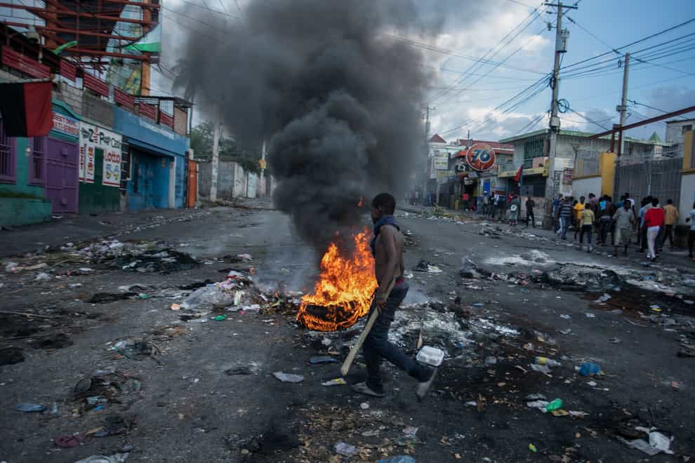A man walks past burning tyres set up by protesters demanding the resignation of Prime Minister Ariel Henry (Odelyn Joseph/AP)