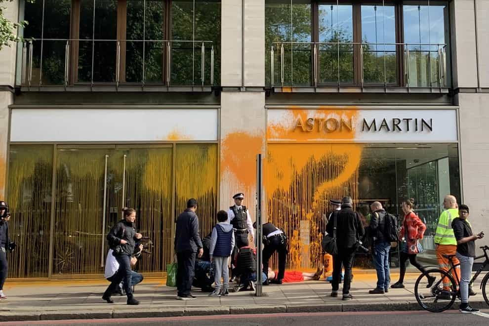Police with Just Stop Oil protesters who have blocked Park Lane in central London and sprayed paint over an Aston Martin car showroom (Naomi Clarke/PA)