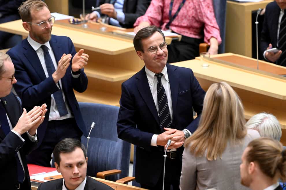 Ulf Kristersson, centre, smiles after being elected as Sweden’s new prime minister at the Parliament in Stockholm (TT via AP)