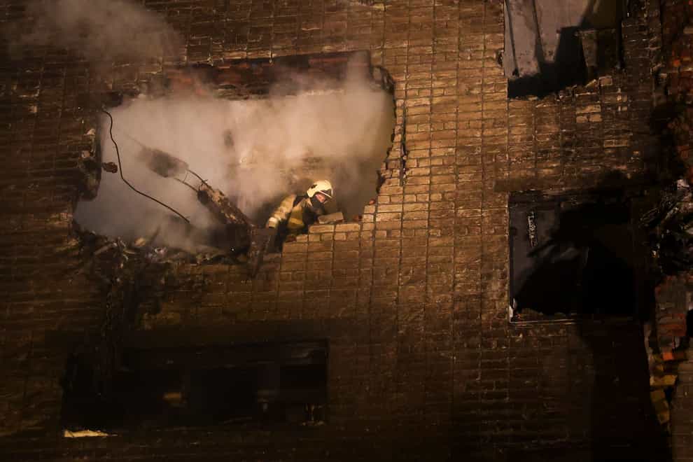 A firefighter is seen inside a damaged apartment after a warplane crashed into a residential area in Yeysk, Russia (AP)