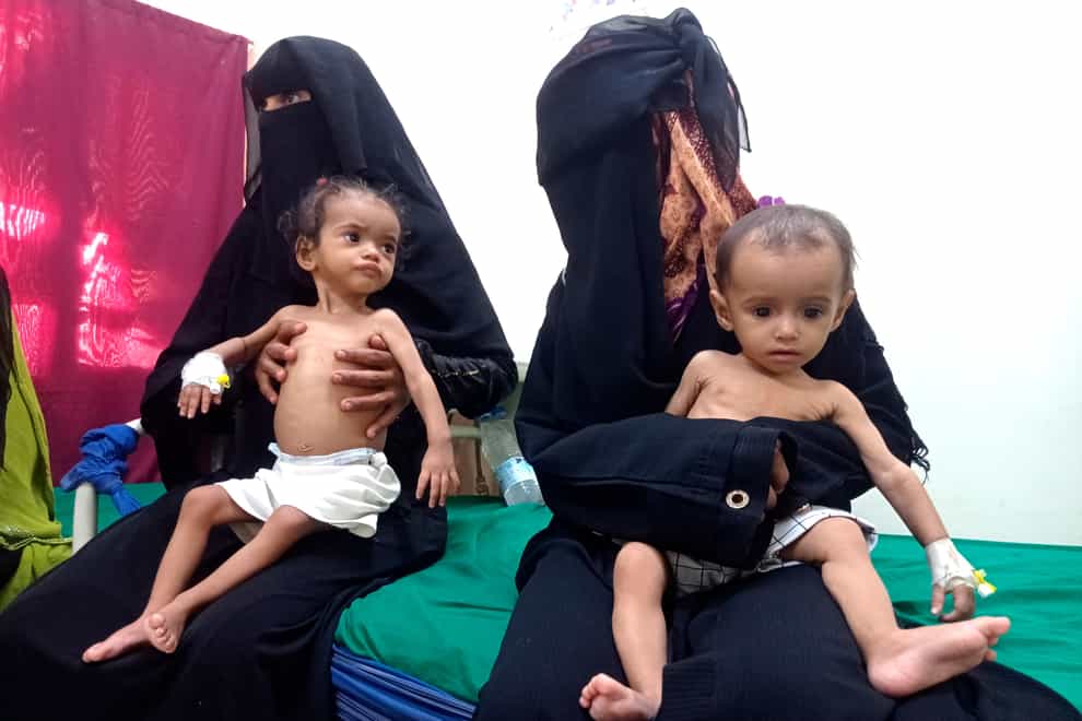 Women hold their malnourished children at Hays Rural Hospital in Hodeida (AP)