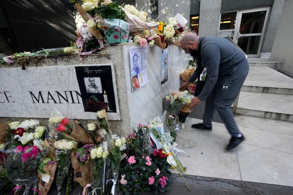 A man lays flowers outside the building where the body of 12-year-old schoolgirl was discovered in Paris (AP)