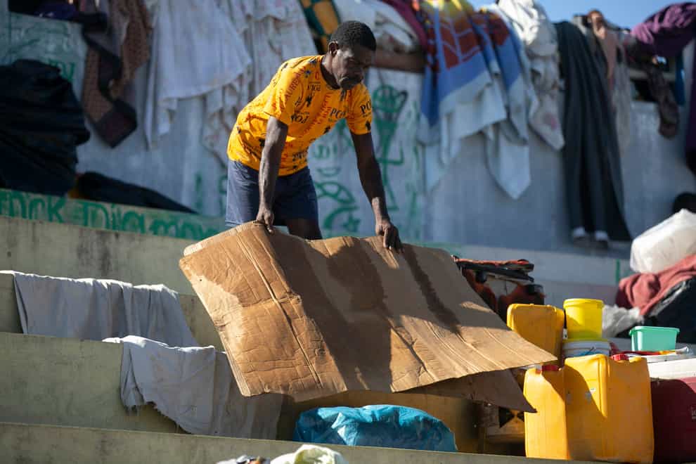 A man dries a piece of cardboard he uses to sleep on at the Hugo Chavez public square transformed into a refuge for families forced to leave their homes due to clashes between armed gangs in Port-au-Prince, Haiti (Odelyn Joseph/AP)
