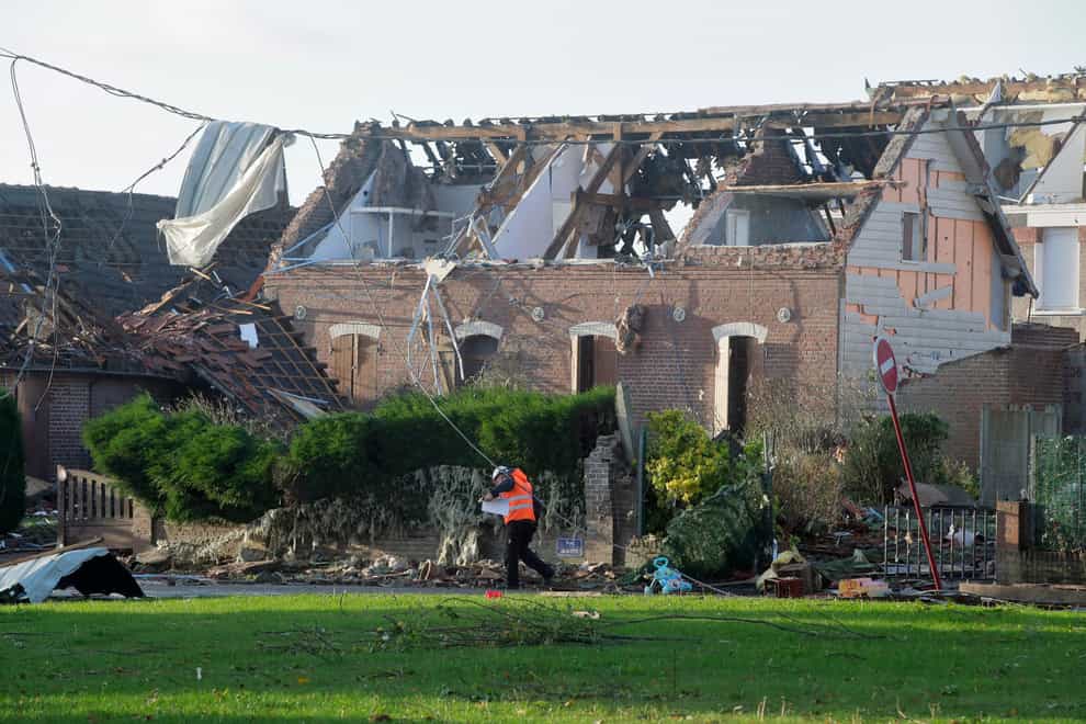 A rescue worker walks next to a house where the roof was destroyed by a tornado in Bihucourt (Michel Spingler/AP)