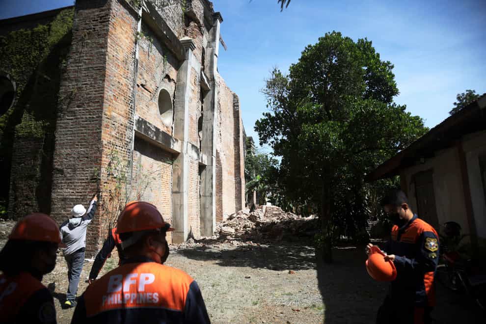 Firefighters stand beside a damaged church in Ilocos Norte after a strong earthquake in the northern Philippines (AP)