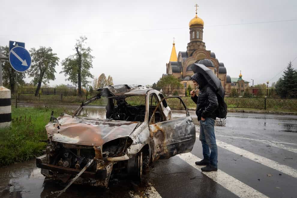 A passer-by looks at a car damaged by Russian shelling in central Bakhmut, Donetsk (AP Photo/Efrem Lukatsky)