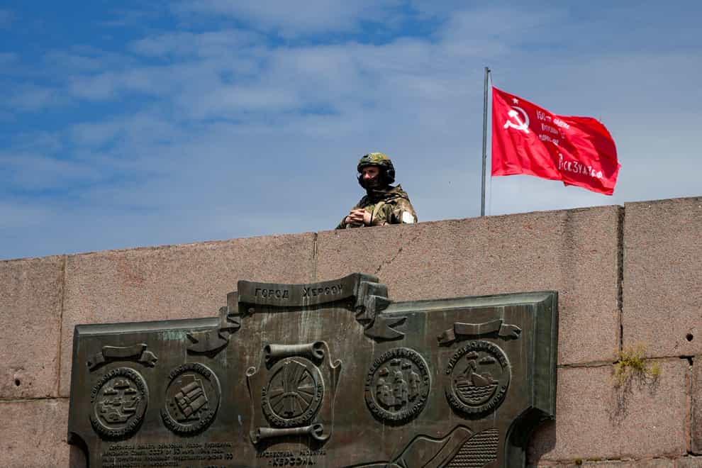 FILE – A Russian soldier guards an area at the Alley of Glory exploits of the heroes – natives of the Kherson region, who took part in the liberation of the region from the Nazi invaders, in Kherson, Kherson region, south Ukraine, on May 20, 2022, with a replica of the Victory banner marking the 77th anniversary of the end of World War II right in the background. Ukrainian forces pressing an offensive in the south have zeroed in on Kherson, a provincial capital that has been under Russian control since the early days of the invasion. This photo was taken during a trip organized by the Russian Ministry of Defense. (AP Photo, File)