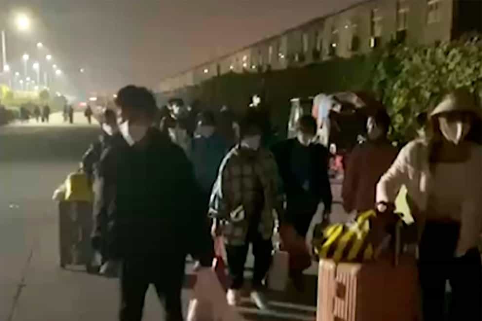 People with suitcases and bags are seen leaving from a Foxconn compound in Zhengzhou (Hangpai Xingyang via AP)