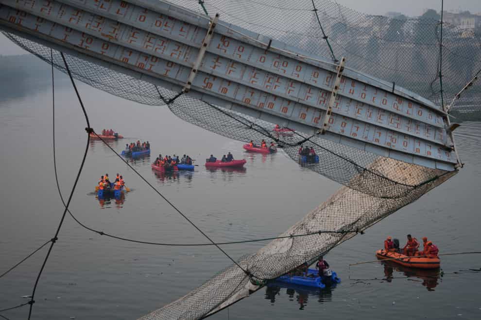 Rescuers on boats search in the Machchu river next to a cable suspension bridge that collapsed in Morbi town of western state Gujarat, India (Ajit Solanki/AP)