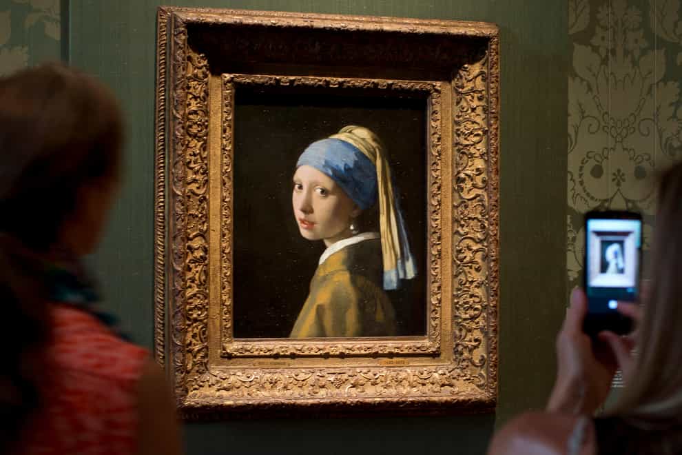 Visitors take pictures of Johannes Vermeer’s Girl with a Pearl Earring (Peter Dejong/AP/PA)