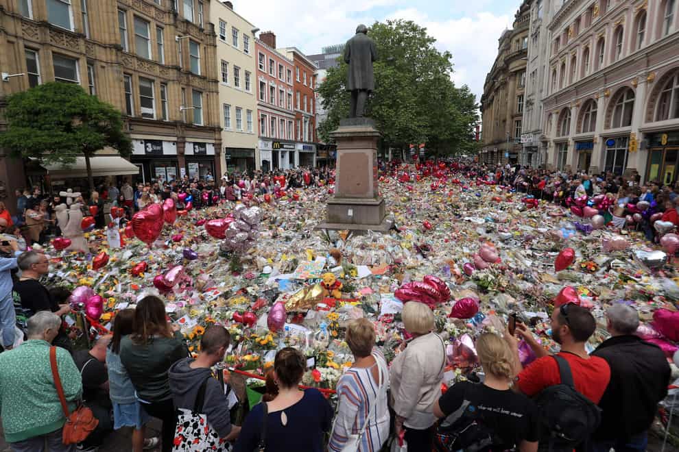 People look at flowers and tributes left in St Ann’s Square in Manchester following the Manchester Arena terror attack (Danny Lawson/PA)